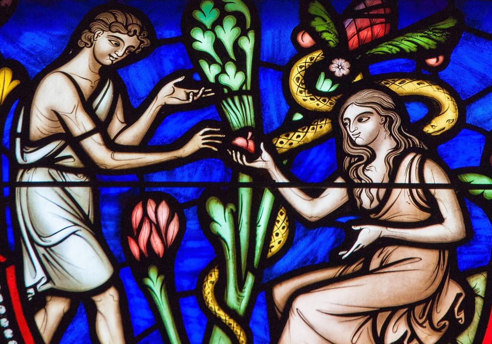 BRUSSELS, BELGIUM - JULY 26, 2012: Adam and Eve eating the Forbidden Fruit in the Garden of Eden on a stained glass window in the cathedral of Brussels.